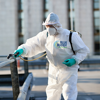 Male cleaner in protective suit disinfecting public area in the city due to coronavirus epidemic. Disinfectant worker cleaning city streets during COVID-19 pandemic.